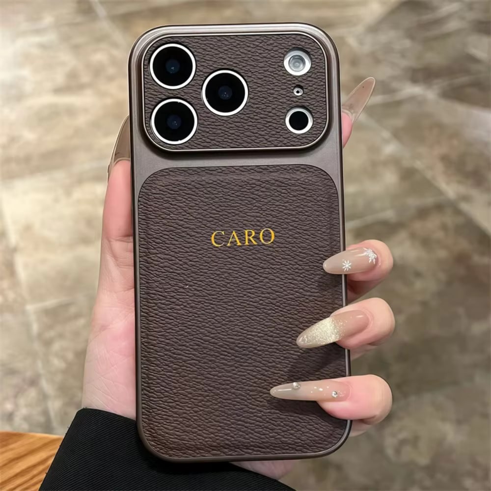 Coque iPhone marron tenue en main, initiales CARO dorées au dos