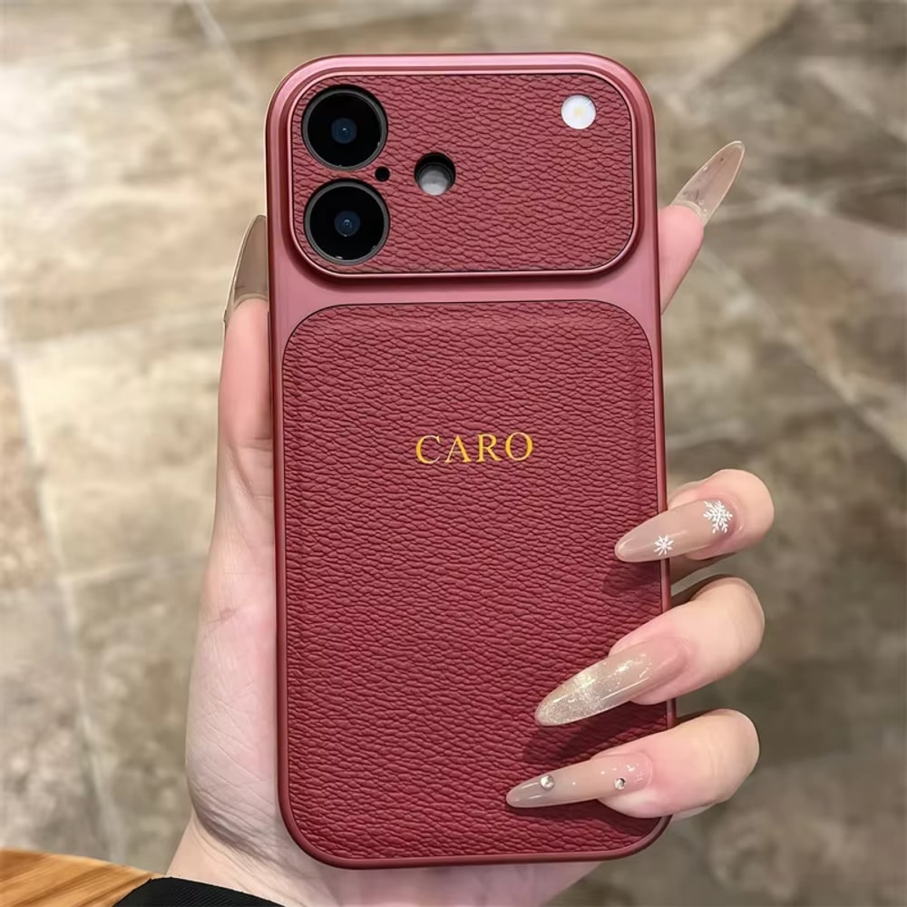 Coque iPhone rouge tenue en main, initiales CARO dorées au dos